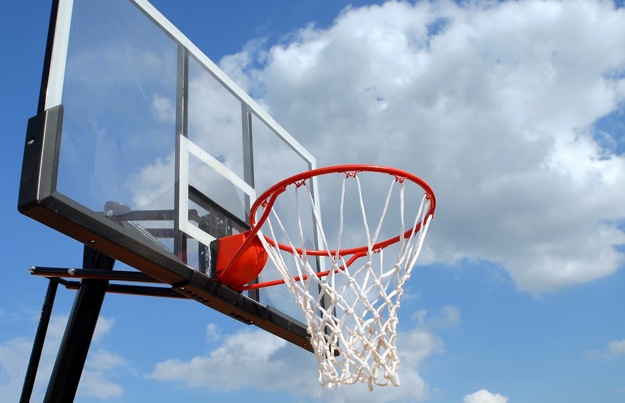 services-01 A basketball hoop and backboard set against a clear blue sky, capturing the essence of outdoor sports.